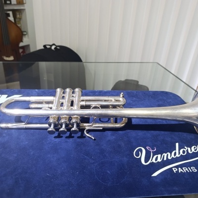 Trompete prateado sobre tecido azul com logo Vandoren Paris