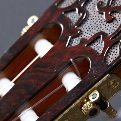 Cabeça de guitarra clássica em madeira escura com tarraxas douradas e detalhes decorativos