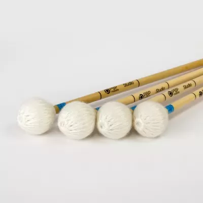 Quatro baquetas de percussão com pontas brancas e cabos de madeira claros sobre fundo branco