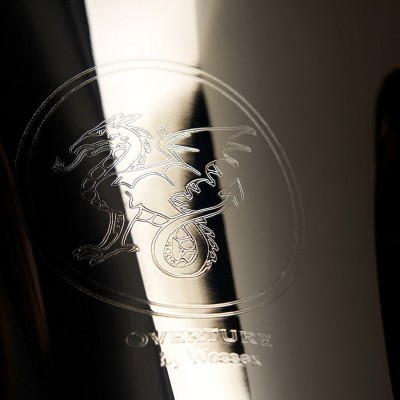 Superfície metálica com gravura de dragão e texto OWERTURE by WESSER