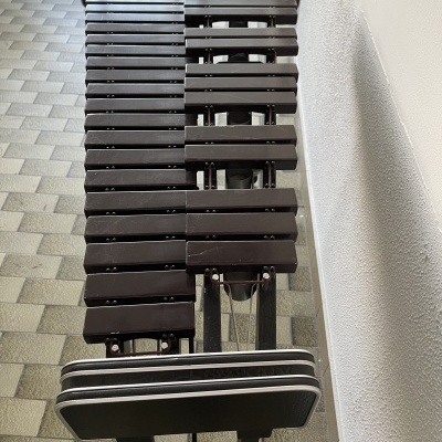 Marimba preta sobre suporte metálico contra parede branca em chão de azulejos cinza