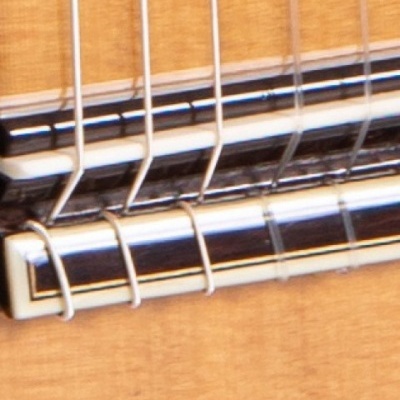 Close-up da ponte e cordas de uma guitarra clássica de madeira clara