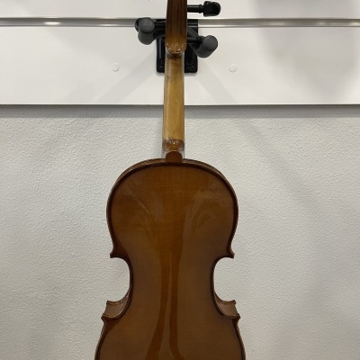 Violino castanho claro visto de trás pendurado numa parede branca