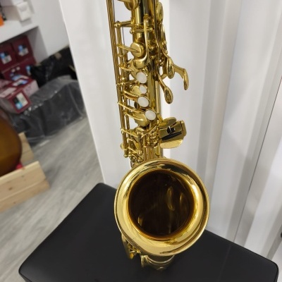 Saxofone tenor dourado com teclas brancas sobre banco preto