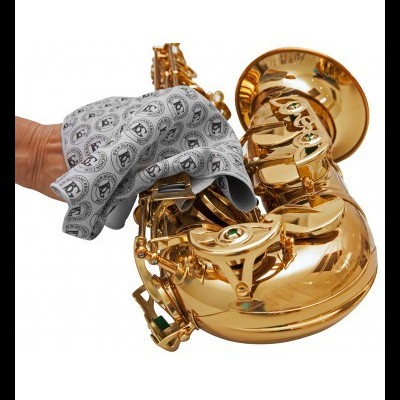 Saxofone dourado a ser limpo com pano cinza estampado