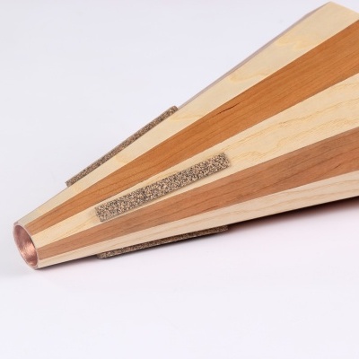 Objeto cónico de madeira com faixas claras e escuras, faixas texturizadas e ponta metálica