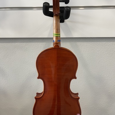 Violino castanho-avermelhado de madeira pendurado numa parede cinzenta.