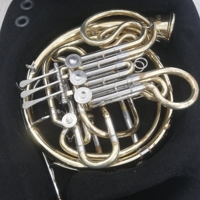 Trompa dourada e prateada com quatro pistões numa mala preta