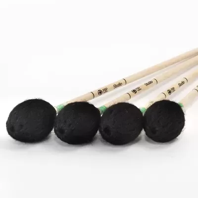 Quatro baquetas de percussão com cabeças de feltro preto e cabos de madeira clara