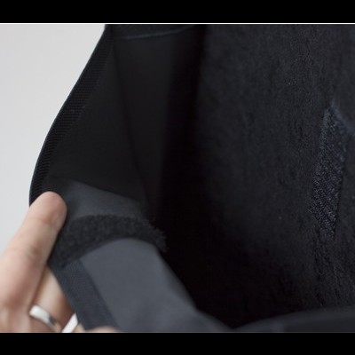 Interior de produto preto com fecho de velcro e mão segurando a borda