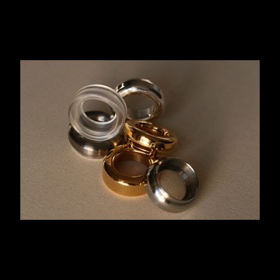 Cinco anéis de materiais e cores variadas sobre superfície neutra