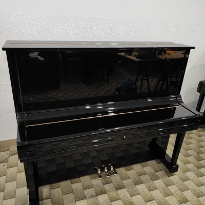 Piano vertical preto com acabamento brilhante e pedais metálicos