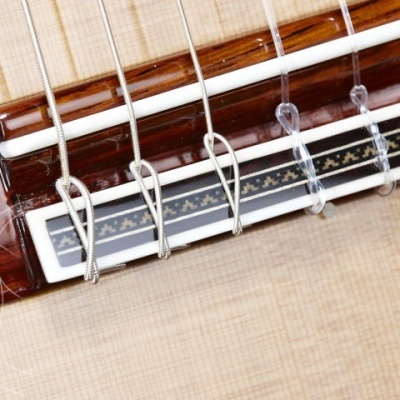 Ponte de guitarra clássica em madeira clara com cordas e padrão decorativo