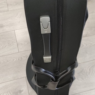 Estojo rígido preto com fecho preto e pega metálica num chão de madeira clara