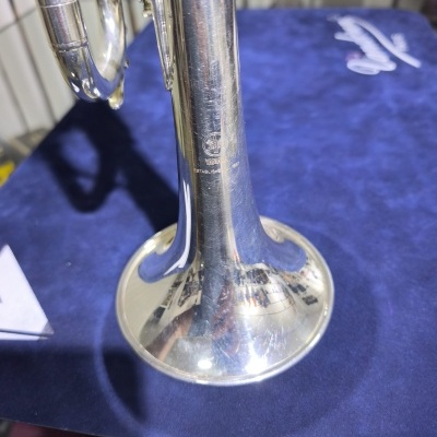 Trompete prateado com logo Yamaha em fundo azul.
