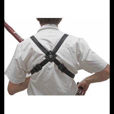 Pessoa de costas com camisa branca e alças pretas em X, segurando clarinete