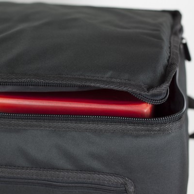 Mala preta em tecido, parcialmente aberta com objeto vermelho dentro