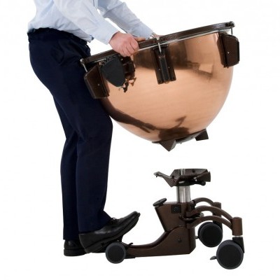 Bombo de latão com suporte móvel e rodas, sendo levantado por uma pessoa.