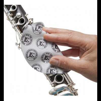 Mão a limpar flauta prateada com pano branco estampado com logotipo BG.