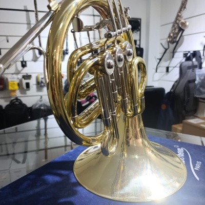 Instrumento musical de latão dourado com válvulas em superfície azul