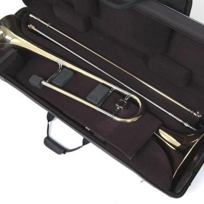 Trombone dourado dentro de estojo rígido preto com interior acolchoado roxo