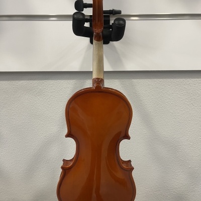 Violino castanho pendurado em suporte preto numa parede branca