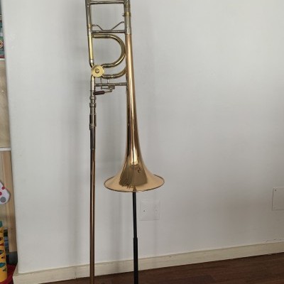 Trombão dourado em suporte preto sobre chão de madeira