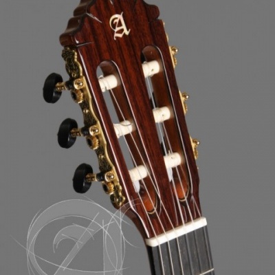 Cabeça de guitarra clássica em madeira escura com tarraxas douradas e letra A branca.