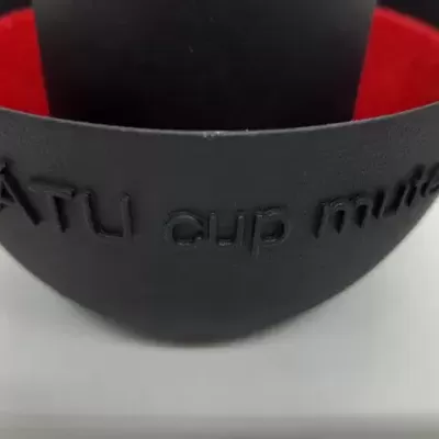 Taça preta fosca com interior vermelho e inscrição TÁTU cup mute em relevo