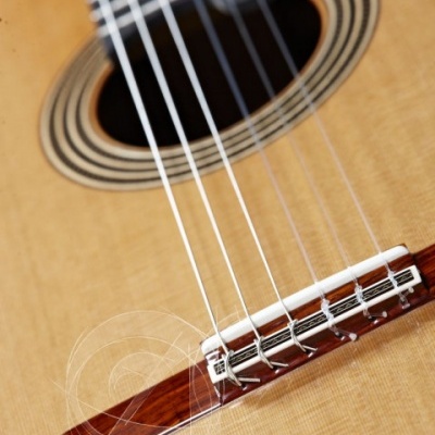 Guitarra clássica de madeira clara com cordas e boca detalhada