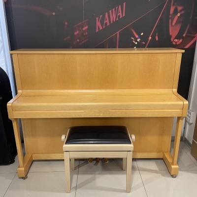 Piano vertical em madeira clara com banco e painel com texto KAWAI MP7