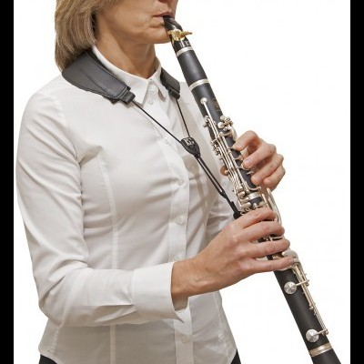 Mulher tocando clarinete com camisa branca e suporte de couro preto