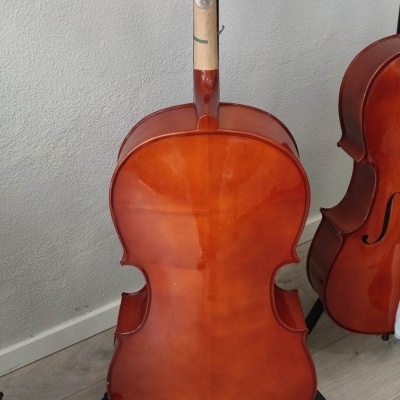 Violoncelo castanho avermelhado com suporte preto sobre chão claro