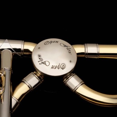 Instrumento de sopro dourado com válvulas e inscrição Open De Luxe