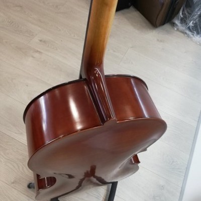 Guitarra clássica de madeira castanho-avermelhada apoiada num suporte no chão de madeira