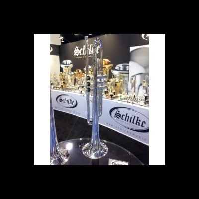 Trompete prateado com pistões pretos em montra com logo SCHILKE