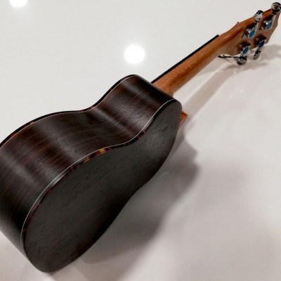 Ukulele em madeira escura e clara sobre superfície branca