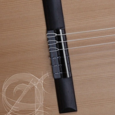 Ponte de guitarra clássica preta com cordas sobre tampo de madeira clara e padrões brancos decorativos