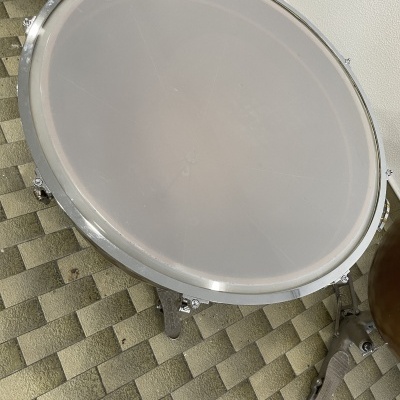 Tambor de percussão EVANS com pele branca e aro metálico sobre chão geométrico