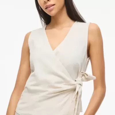 Top creme sem mangas com laço lateral, combinado com saia creme com botões frontais