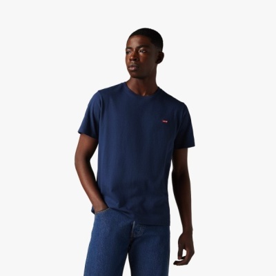 Homem com t-shirt azul escura e jeans azuis em fundo branco