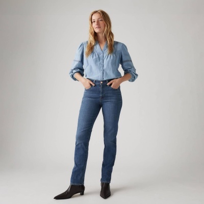 Mulher com camisa azul clara e jeans azul escuro com botas pretas