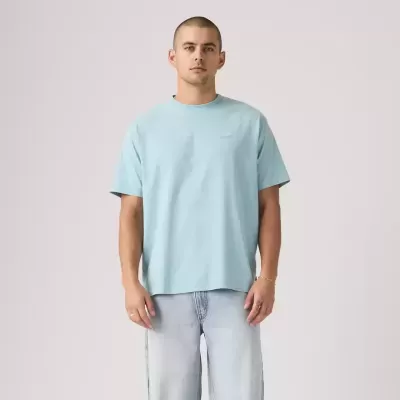 T-shirt azul claro de algodão com texto LOAF TEES no peito, usada por modelo com calças de ganga claras em fundo cinza