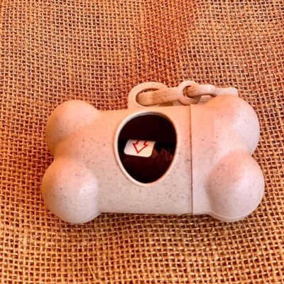 Dispenser de sacos para resíduos caninos bege em forma de osso sobre tecido de juta