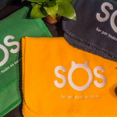 Toalhas coloridas com bordado branco e planta sobre superfície plana