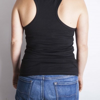 Pessoa de costas com camisola preta sem mangas e jeans azuis