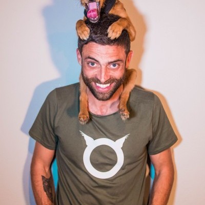 Homem com cão pequeno nos ombros e t-shirt verde com símbolo branco