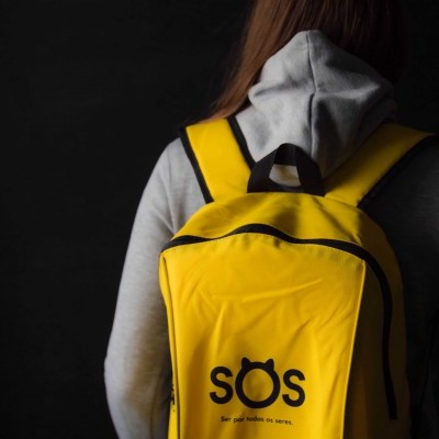 Mochila amarela com texto 'sós' e frase inspiradora