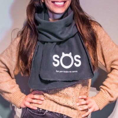 Cachecol cinzento escuro com texto branco SOS usado por mulher com camisola bege