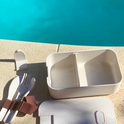 Marmita branca com tampa e talheres de plástico ao lado de piscina